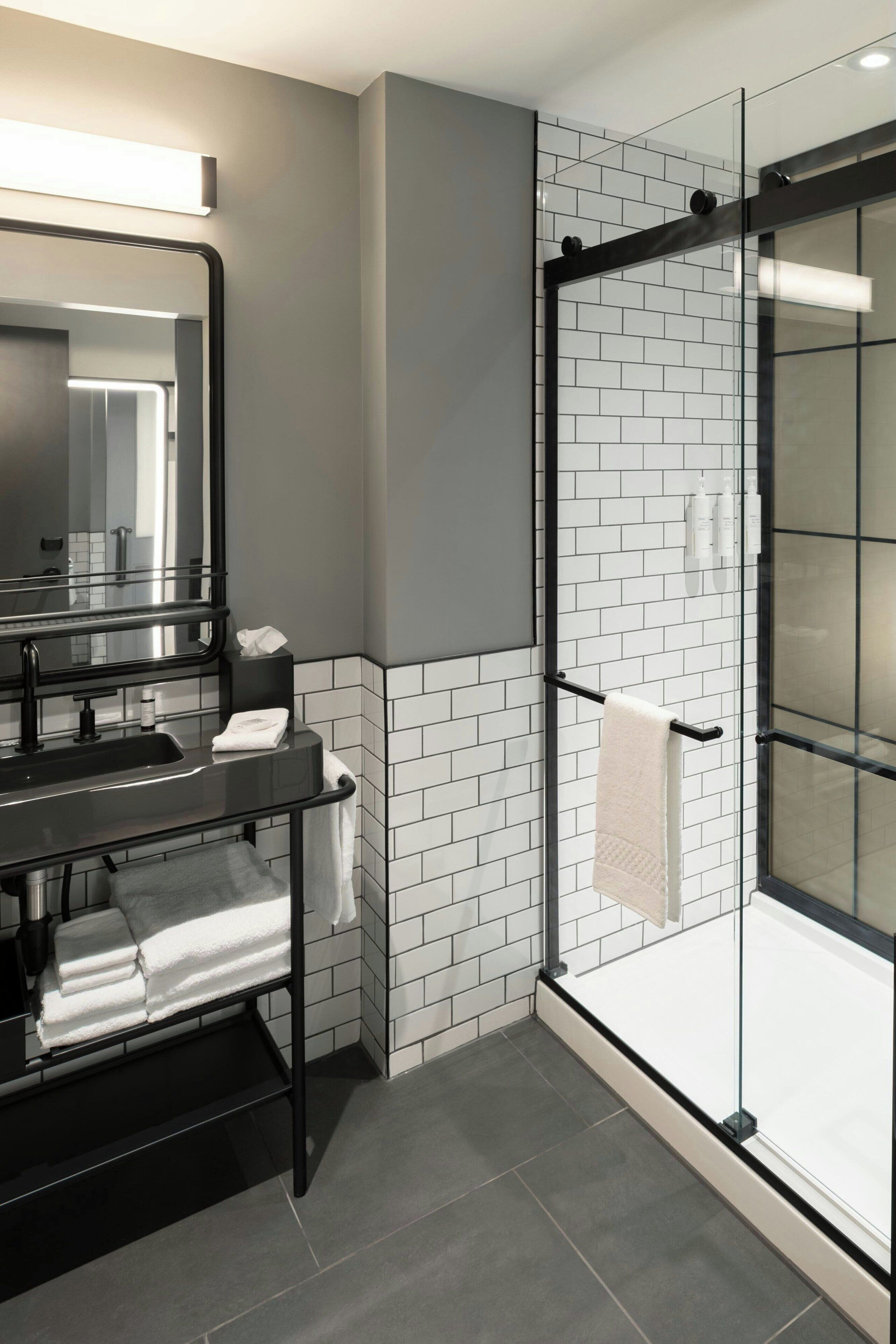 A modern bathroom with a glass shower enclosure, a black sink, and a mirror.