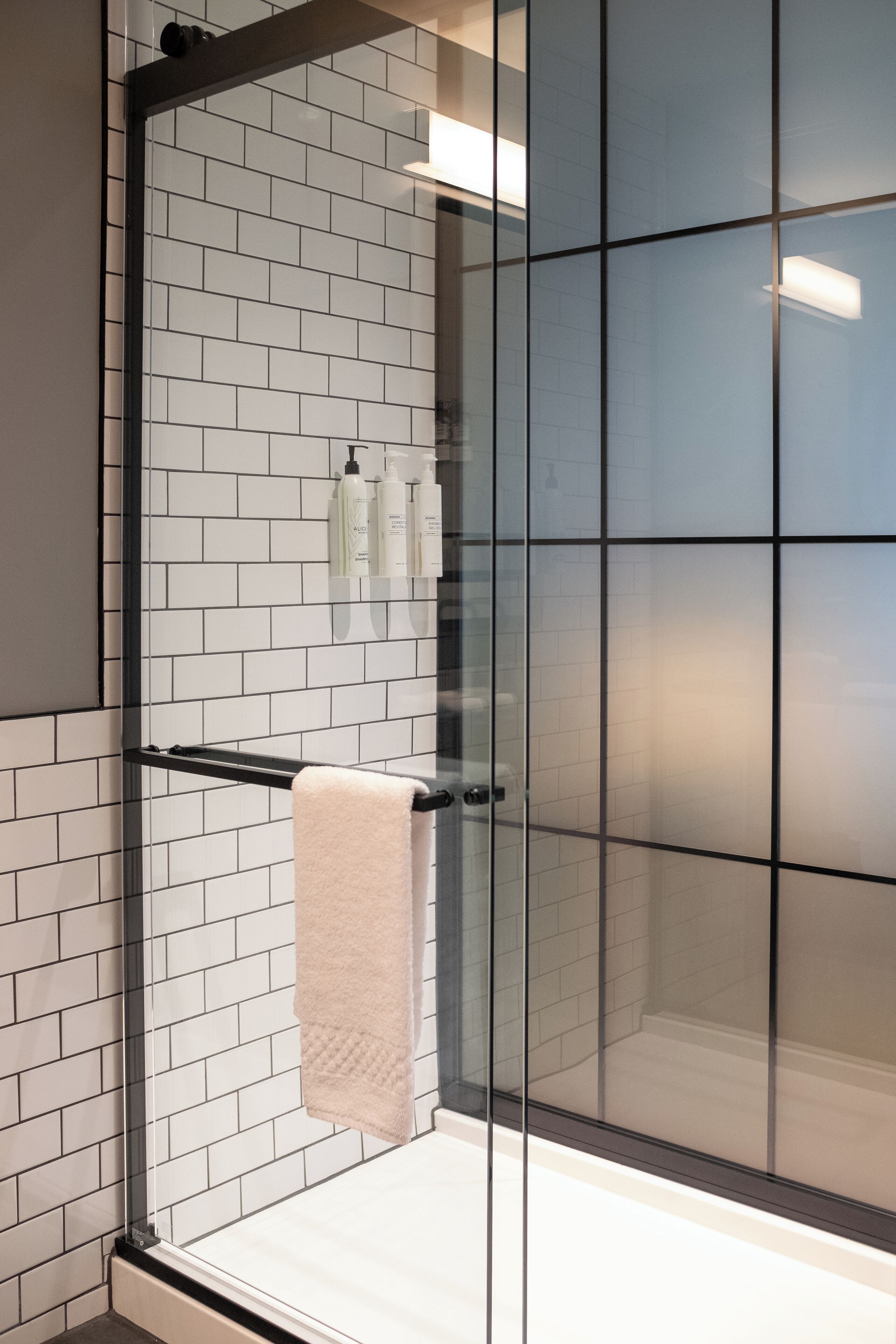 A modern bathroom with white subway tiles, a glass shower enclosure, and a towel rack.