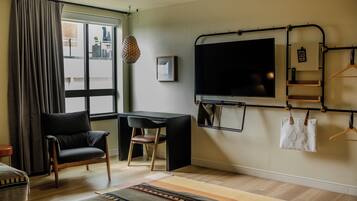 Une chambre d’hôtel équipée d’un bureau, d’une chaise, d’une télévision et offrant une vue sur la ville par la fenêtre.