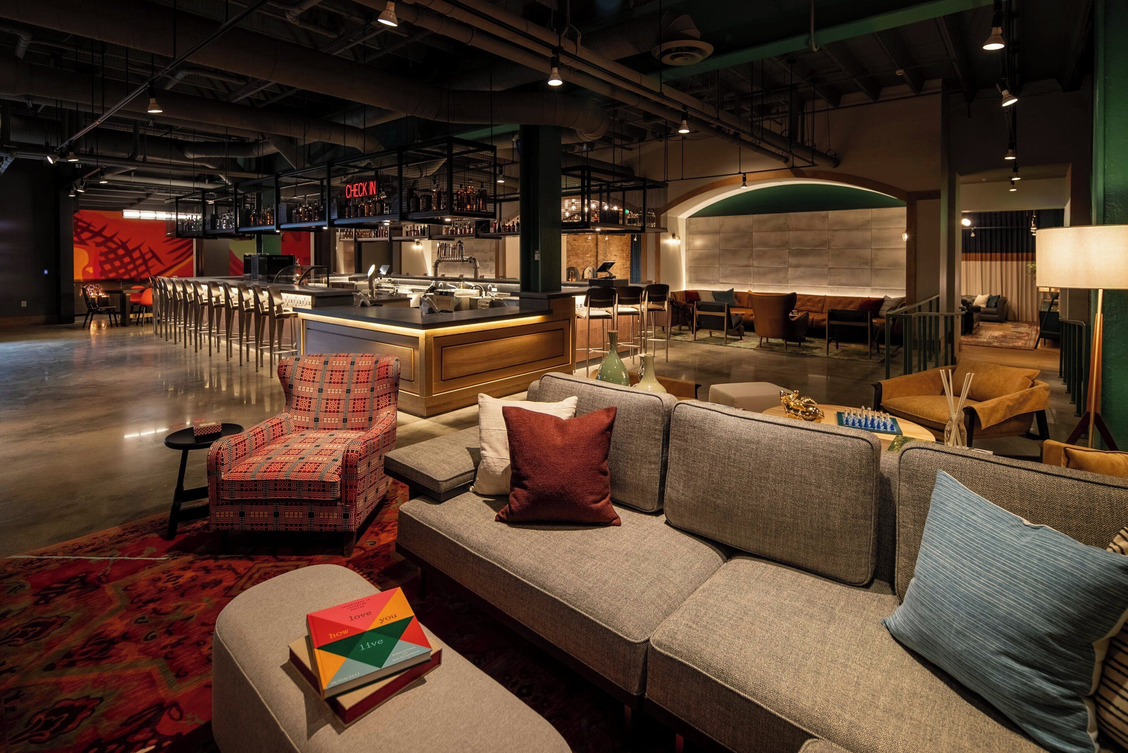 A modern lounge area with a bar, seating arrangements, and a check-in counter.