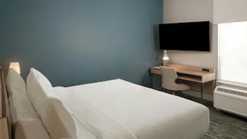 A hotel room with a bed, a desk, a chair, a TV, and a window.