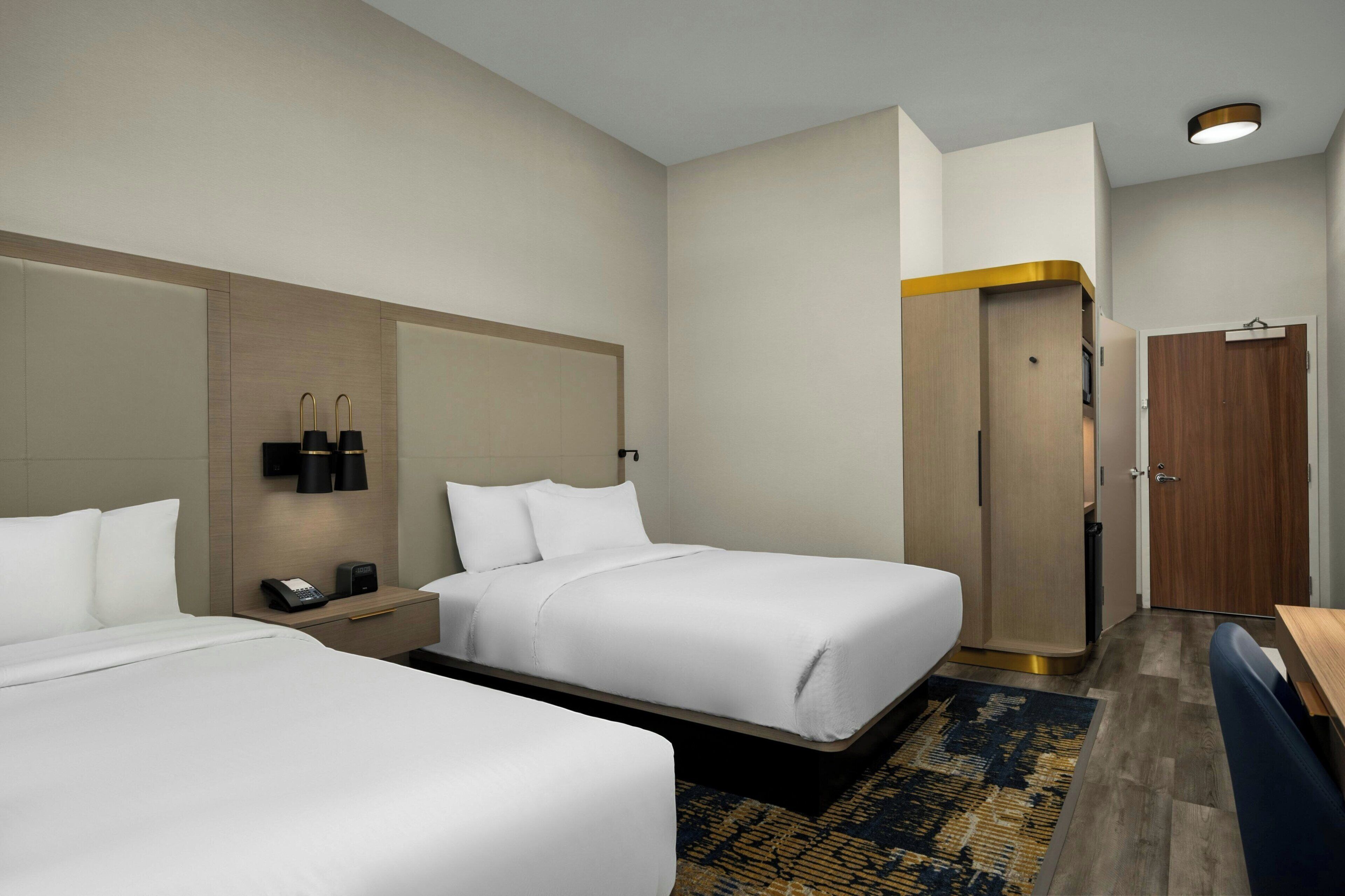 Une chambre d’hôtel avec deux lits, un bureau, une armoire et une salle de bain.
