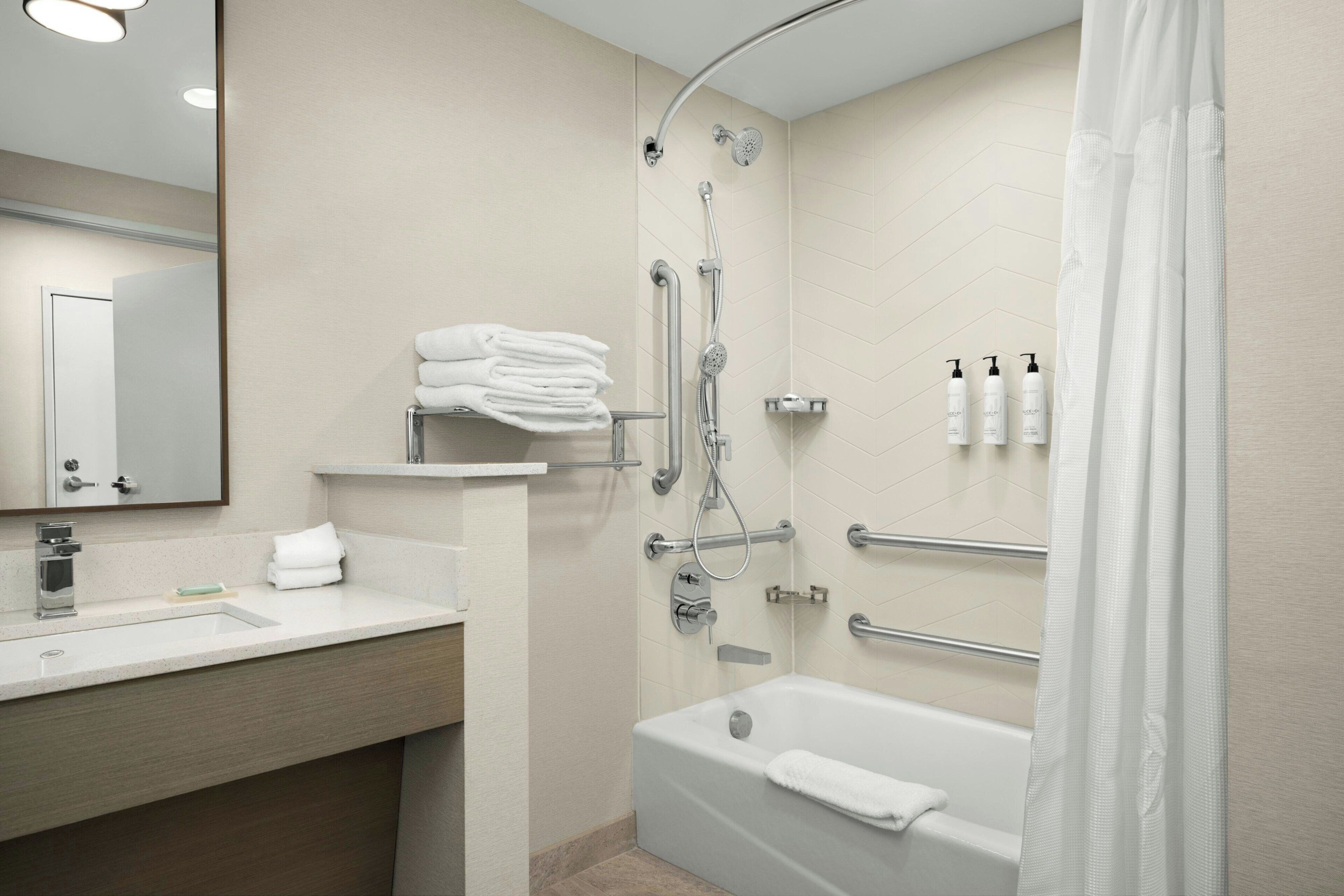 A modern bathroom with a bathtub, shower, and vanity.