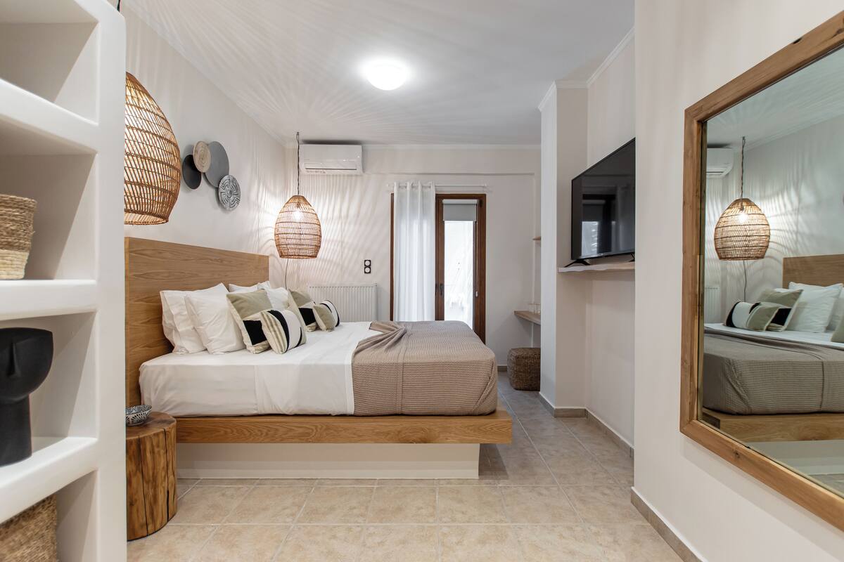 A modern bedroom with a large bed, bedside tables, a TV, and a mirror.