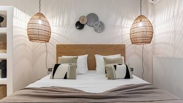 Una cama bien hecha con un cabecero de madera, dos lámparas de mimbre colgantes y una pared decorada con platos.