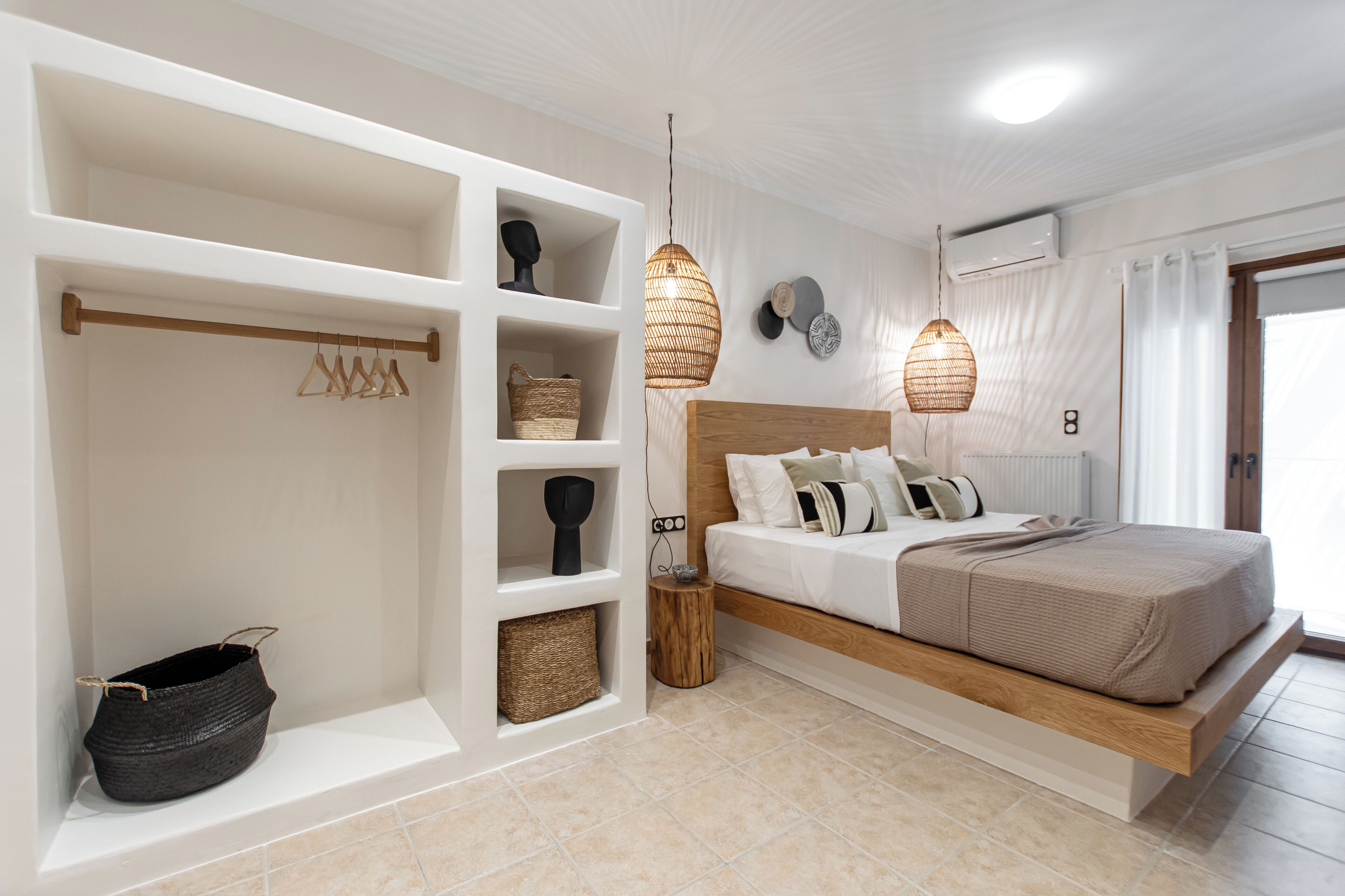 Une chambre moderne avec un lit en bois, des étagères blanches et des luminaires en fibres tressées.