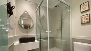 A modern bathroom with a glass-enclosed shower, a white sink, and a toilet. - Three Suites just a few steps from the beach (Ipanema Rio de Janeiro)
