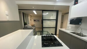 A modern kitchen with a gas stove, a microwave, and a sink. - Three Suites just a few steps from the beach (Ipanema Rio de Janeiro)
