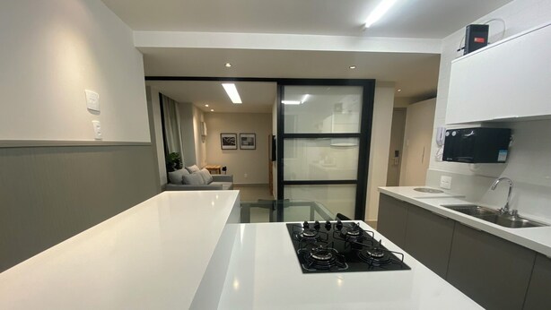A modern kitchen with a central island, a built-in stove, and a microwave. - Three Suites just a few steps from the beach (Ipanema Rio de Janeiro)