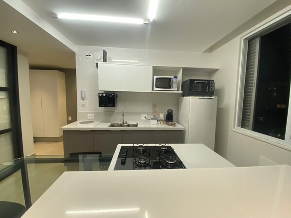 Una cocina moderna con estufa a gas, microondas y cafetera.