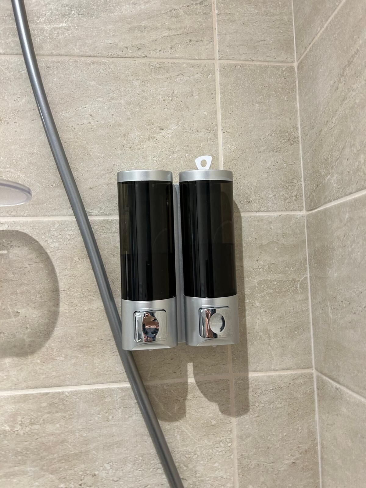 Zwei schwarze und silberne Behälter an einer gefliesten Wand.