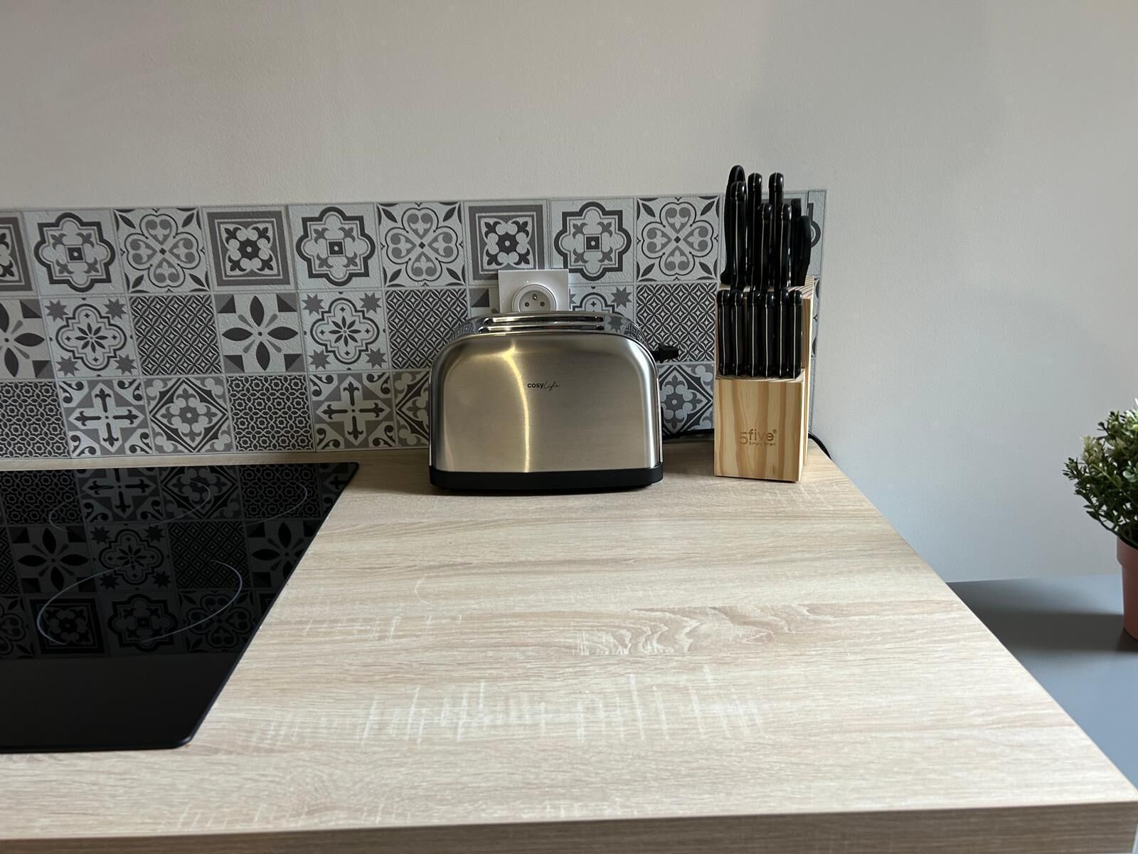 Una cucina con un tostapane, un set di coltelli e un pannello di fondo decorato.