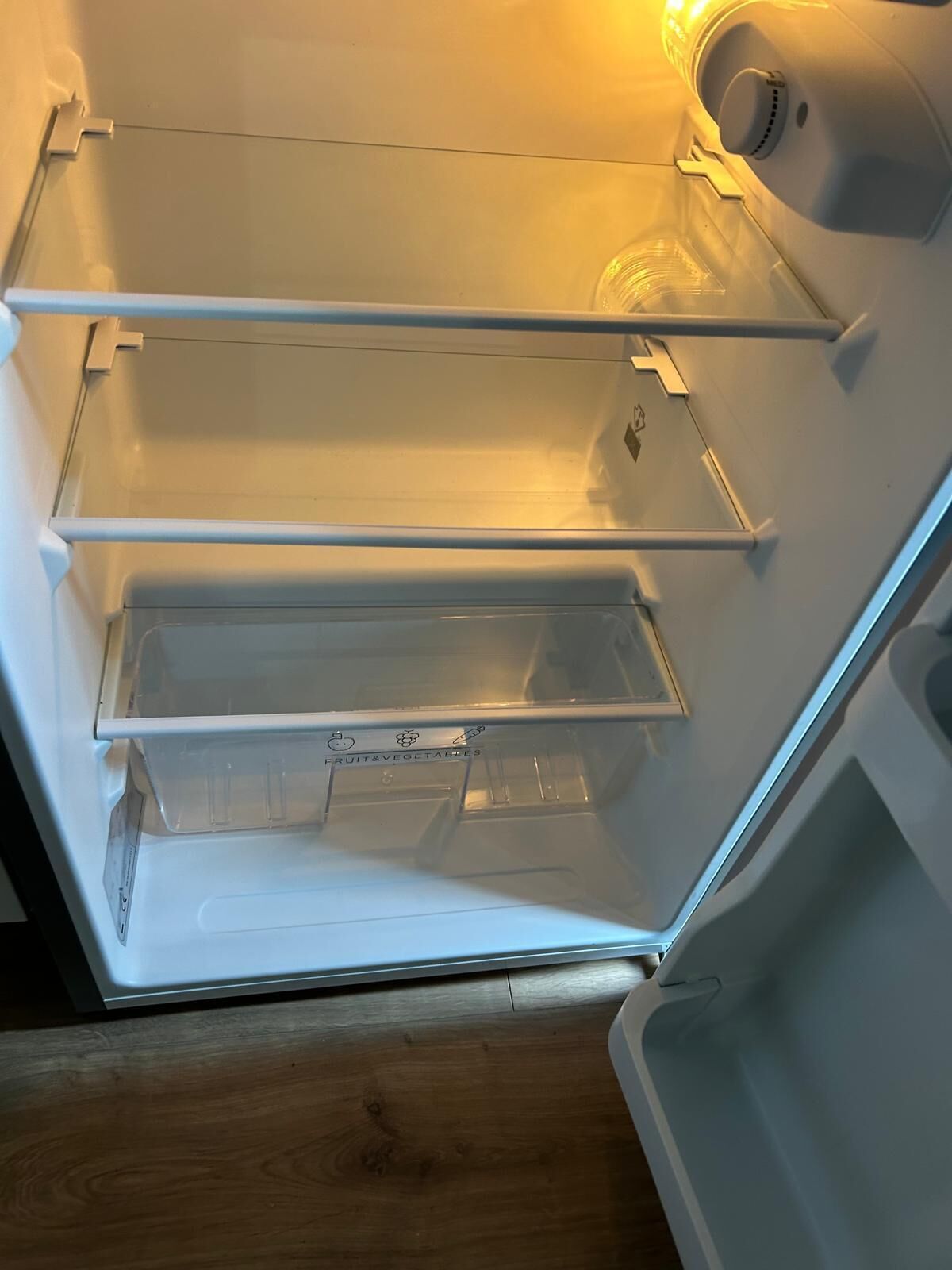 An open refrigerator with three shelves and a freezer compartment.