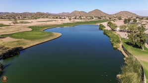 Un parcours de golf avec un grand étang, entouré de zones résidentielles et de montagnes.