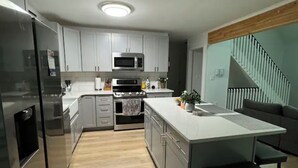 Eine moderne Küche mit Edelstahlgeräten, grauen Schränken und Holzboden.
