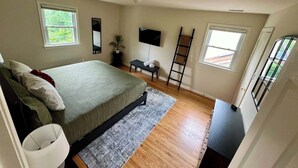 Ein Schlafzimmer mit Bett, Fernseher, einer Leiter und einem Fenster.