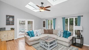 Un salon spacieux avec un canapé d’angle, une table basse et un ventilateur de plafond.