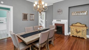 Une salle à manger avec un lustre, une cheminée et une horloge murale.