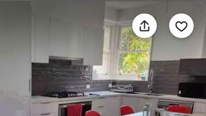 A modern kitchen with white cabinets, a red dining table, and red chairs. - LUXURY HOME  WITH KING BED, HOT TUB, WiFi, AC , Arcade games Netflix sleeps 9  (Portland)