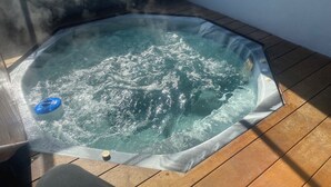 A hot tub with a wooden deck and a window. - LUXURY HOME  WITH KING BED, HOT TUB, WiFi, AC , Arcade games Netflix sleeps 9  (Portland)