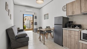 A modern kitchen with a refrigerator, coffee maker, and dining table. - Seafront Apartment in Chania 7 (Chania)