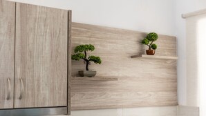 A kitchen with wooden cabinetry and two shelves holding potted plants. - Seafront Apartment in Chania 7 (Chania)