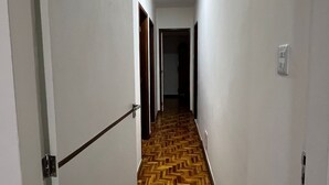 A hallway with a wooden parquet floor, white walls, and a door on the left. - Spacious 3-bedroom apartment in amazing Boa Viagem Recife with AC, WiFi (Boa Viagem Recife)