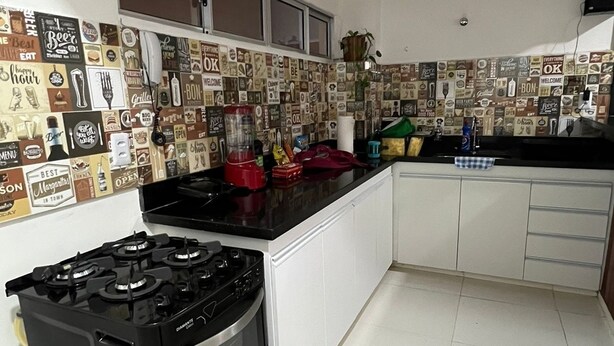 A kitchen with a gas stove, oven, and a backsplash with various food-related signs. - Spacious 3-bedroom apartment in amazing Boa Viagem Recife with AC, WiFi (Boa Viagem Recife)