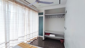 Ein Zimmer mit Bett, Deckenventilator, Kleiderschrank und Kleiderständer.