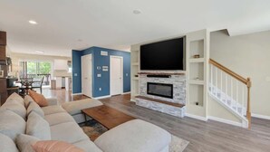 Un salón amplio con un sofá modular grande, una chimenea y un televisor montado en la pared.