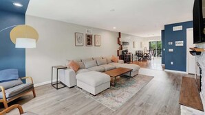 Una sala moderna con un sofá modular, una mesa de centro y un comedor al fondo.