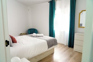 Un dormitorio con cama, una silla, cómoda y espejo.