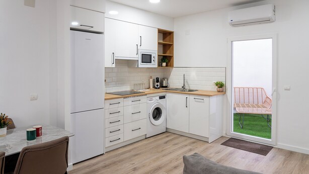 Una cocina compacta con lavadora, microondas y lavabo.