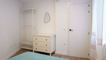 Un dormitorio con cama, armario, cómoda, espejo y puerta.