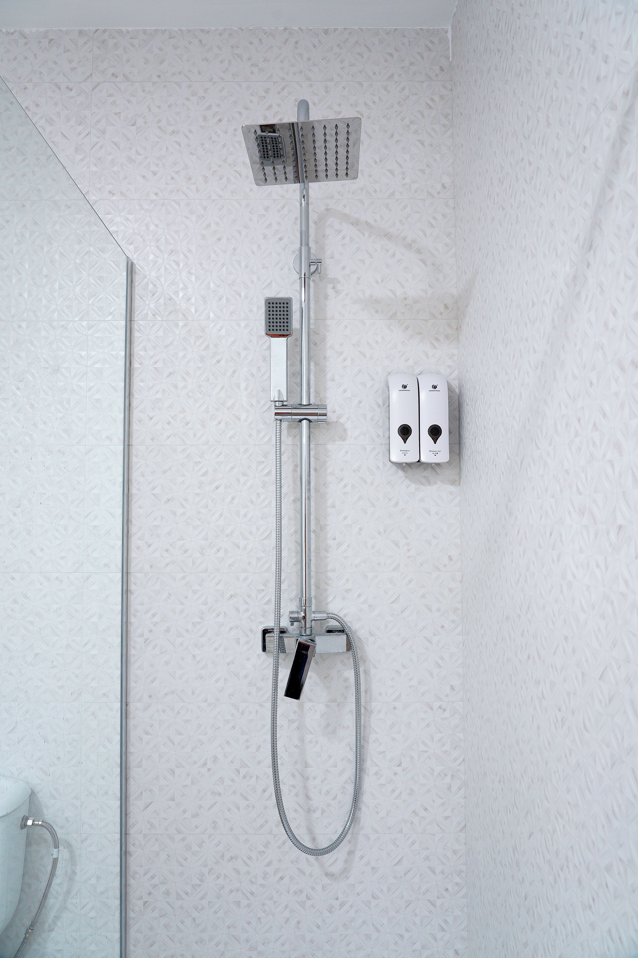Ducha con cabezal de ducha manual, panel de control en la pared y manguera para ducha de mano.