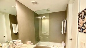 Une salle de bain moderne avec un grand miroir, un lavabo, des toilettes et une baignoire.