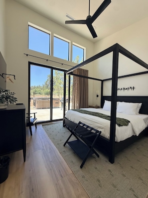 Quarto moderno com cama de dossel, janelas amplas e ventilador de teto.