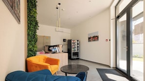 A modern lobby with a reception desk, a vending machine, and seating areas. - TESLA Residence Subotica (Subotica)