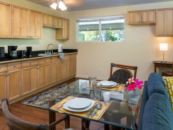 Una cocina con armarios de madera, una mesa de comedor con platos y cubiertos, y una ventana con vistas a la vegetación.