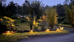 A landscaped garden with pathways, trees, and illuminated lights. - Whole House Rental- Modern Two-Unit Bungalow (Volcano)