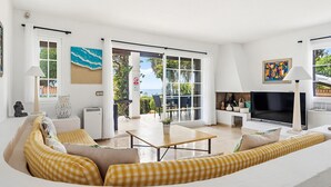 En moderne stue med sofa, fjernsyn og spiseplads med bord og stole.