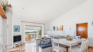 A modern living room with a TV, seating area, dining table, and a view of the outdoors. - Villa Ana by Escape Home (Santo Tomas)