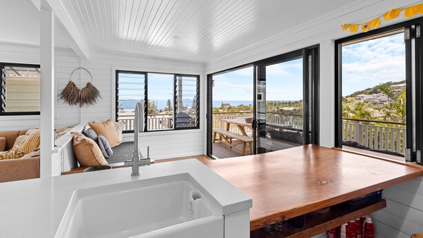 A modern kitchen with a large island, a built-in sink, and a view of the ocean through large windows. - East 20 @ Crescent Head (Crescent Head)