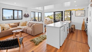 A modern living space with a sofa, coffee table, and a dining area. - East 20 @ Crescent Head (Crescent Head)