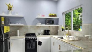 A modern kitchen with white cabinets, a black stove, a microwave, and a window with a view of greenery. - Williams Manor [Across From Ricks Cafe Negril] (Negril)