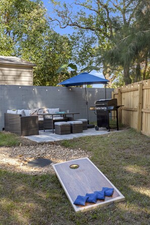 Enjoy al fresco dining and relaxation in this serene outdoor space, featuring a barbecue grill, dining table, and comfortable wicker seating.