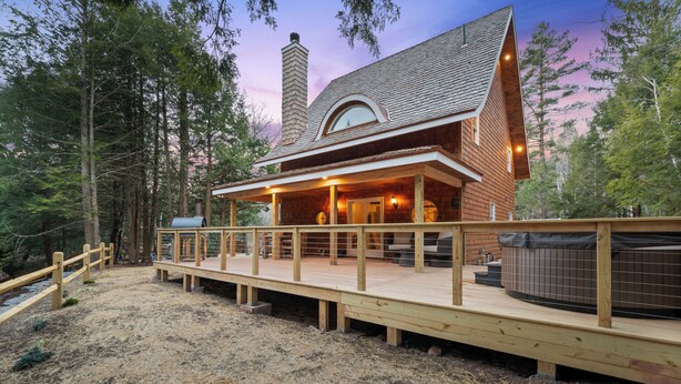 Una cabaña de madera con terraza, jacuzzi y chimenea.