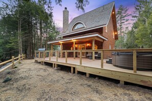 Une cabane en bois avec une terrasse, un jacuzzi et une cheminée.