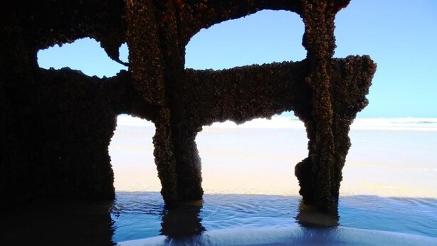 Une structure composée de deux piliers, avec une surface d’eau réfléchissante devant.