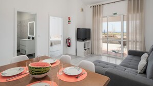 Un salon moderne comprenant un coin repas, un téléviseur et un balcon avec vue.